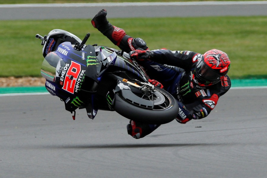 A motorcycle racer falls from his bike on a track.