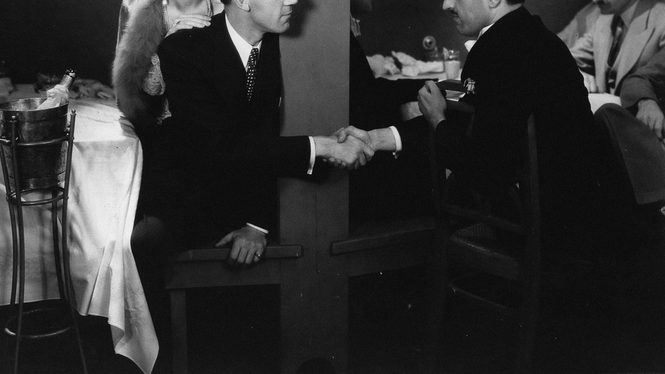 A black and white photo of two men shaking hands in a dark bar