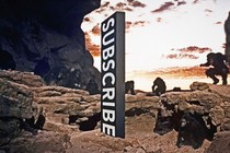 A sign reading "Subscribe" in the center of a rocky landscape featuring apes.