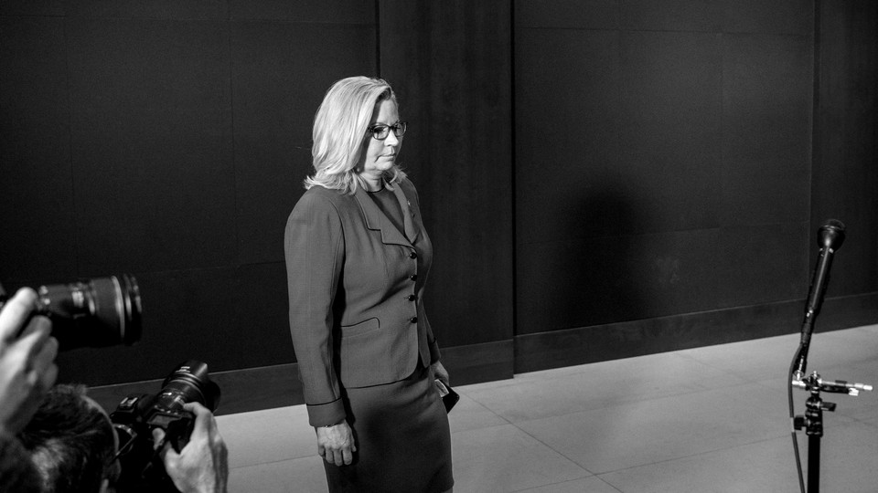 A black and white photo of Liz Cheney standing by herself