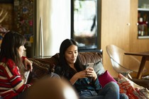 Two women on a sofa; one is holding a phone.