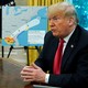 President Trump sits at a desk in front of diagrams of Hurricane Michael's path.