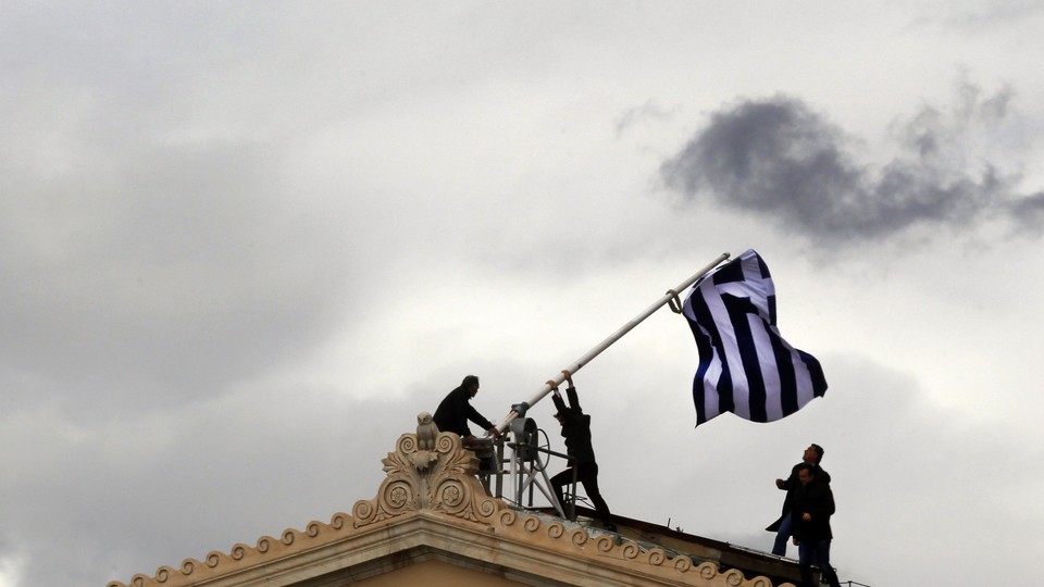 Greek parliament employees raise a mast after they replaced torn-off Greek flag with a new one atop the parliament in Athens Syntagma (Constitution) square on April 18, 2012.