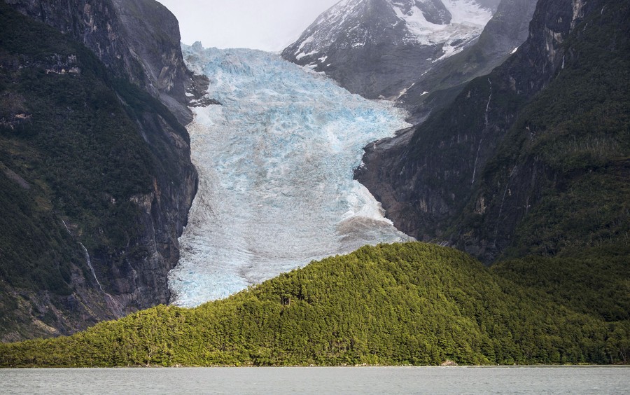 A glacier descends down a steep mountain valley.