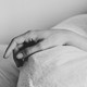 A black and white image of a hand resting on a pillow
