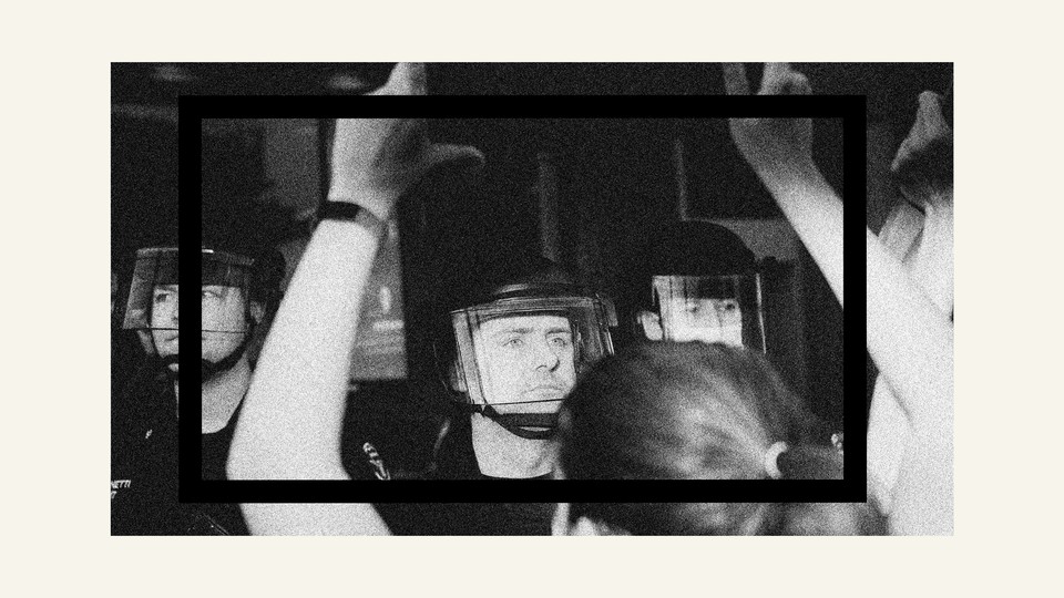 Black-and-white photo of riot police facing protesters