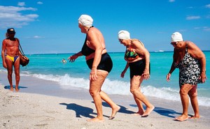 Ladies exiting the ocean looking at a man in a speedo