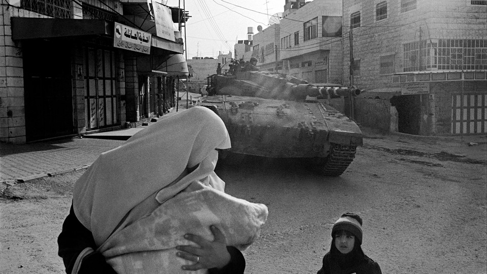 A woman and child in front of a tank