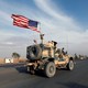 A convoy of U.S. military vehicles travels down a road in Iraq.