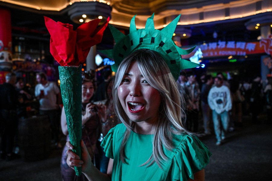 A person wearing a Statue of Liberty costume is photographed in a crowd.