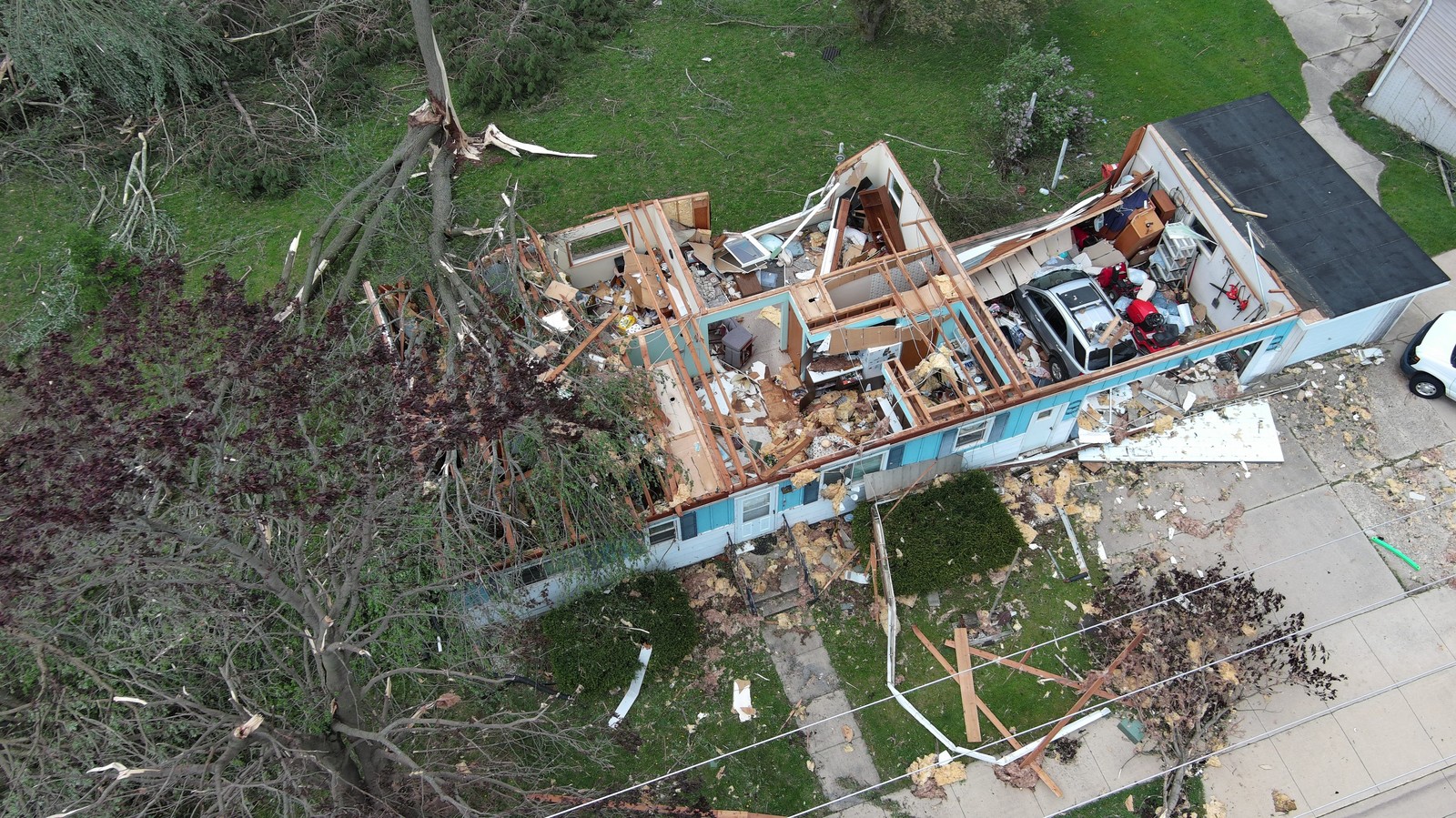 A roof is torn off a home, seen from above.