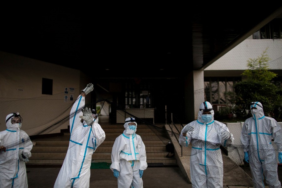 Five people wearing protective equipment set up a wide net in front of a building.