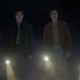 Nancy, Jonathan, Steve and Dustin from Stranger Things stand in a line, holding flashlights in darkness
