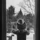 Black-and-white photo of a child looking out the window as it snows