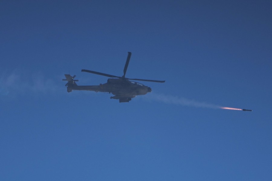 A military helicopter fires a missile, photographed from below.