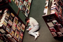 A man reads a book on the ground in a Barnes and Noble