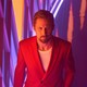 Ryan Gosling in a red suit in front of a vibrant background in "The Gray Man"