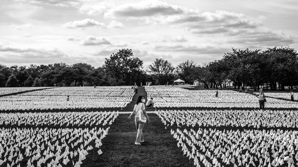 People visit the 'In America: Remember' public art installation near the Washington Monument in September 2021. The installation commemorates all the Americans who have died from COVID-19. It includes more than 650,000 small plastic flags.