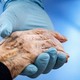 A doctor holds a patient's hand against blue background