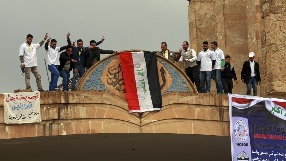 Mosul University students and activists place a national flag at the entrance of their university as they celebrate its liberation from ISIS.