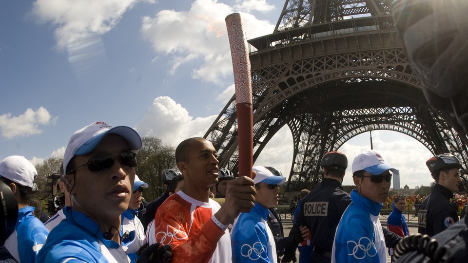 A French athlete, surrounded by Chinese security officers, carries the Olympic torch in Paris in April 2008.