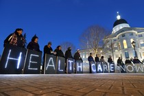 Holding signs, members of a pro-Medicaid group stage a rally outside a government building in Maine.