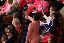 A Representative holds up a sign that reads "SAVE MEDICAID" near a group of congresspeople wearing pink