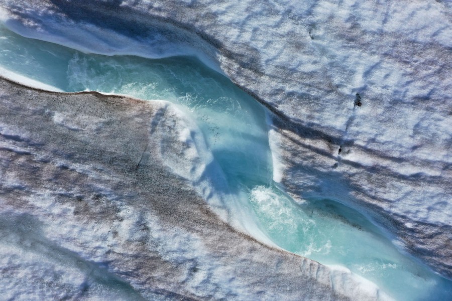 An aerial view of a meltwater stream flowing down a glacier.