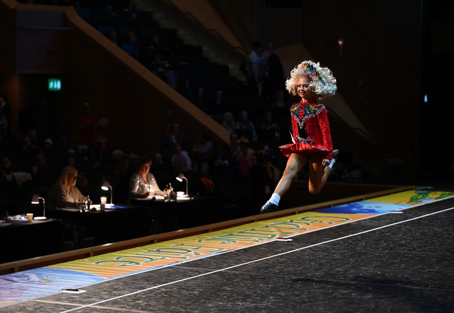 A young dancer performs on stage in front of judges and an audience.
