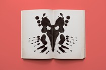 An ink blot in the middle of the pages of an open book.