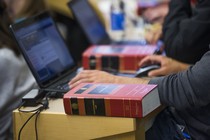 A student working on a laptop with a textbook nearby.