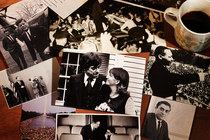 Multiple old pictures and documents next to a brown cardboard box and a cup of coffee