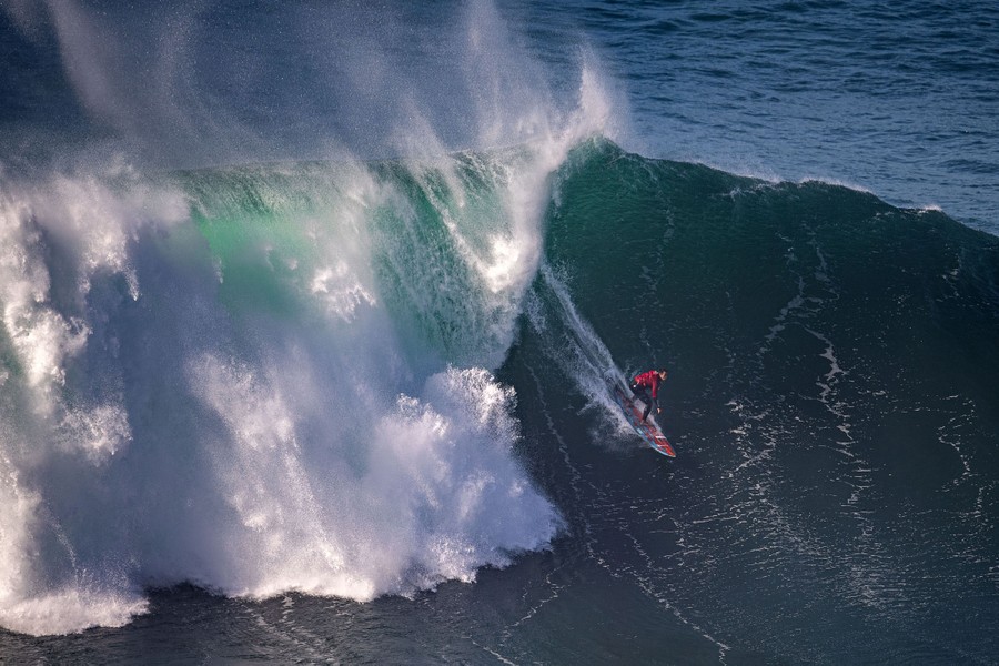 A person surfs on a very large wave.