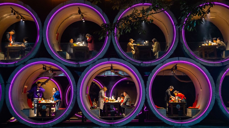 Restaurant customers sit at tables built into concrete pipes that have been stacked on top of one another.