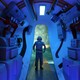A boy stands in a submarine, looking up. 