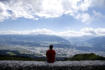 A man sits on a wall and enjoys the view.