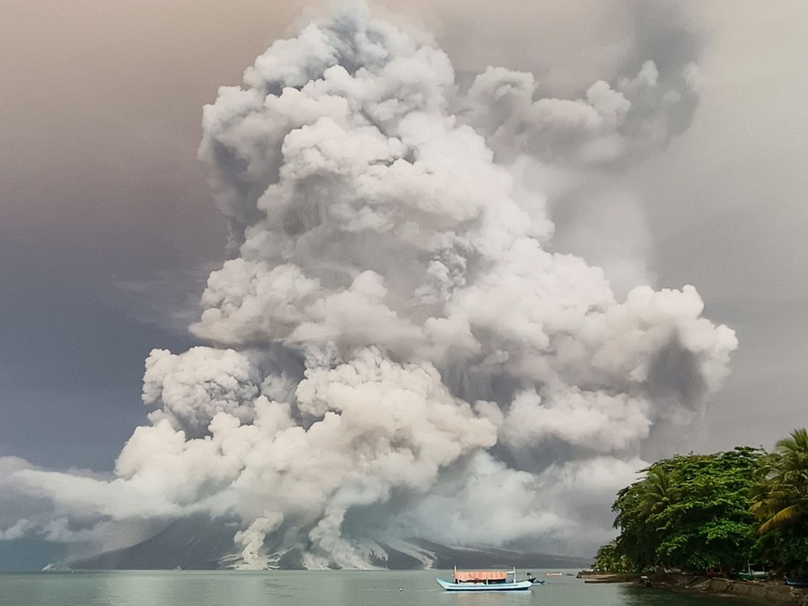 A large plume of gas, steam, and dust rises above a volcano.