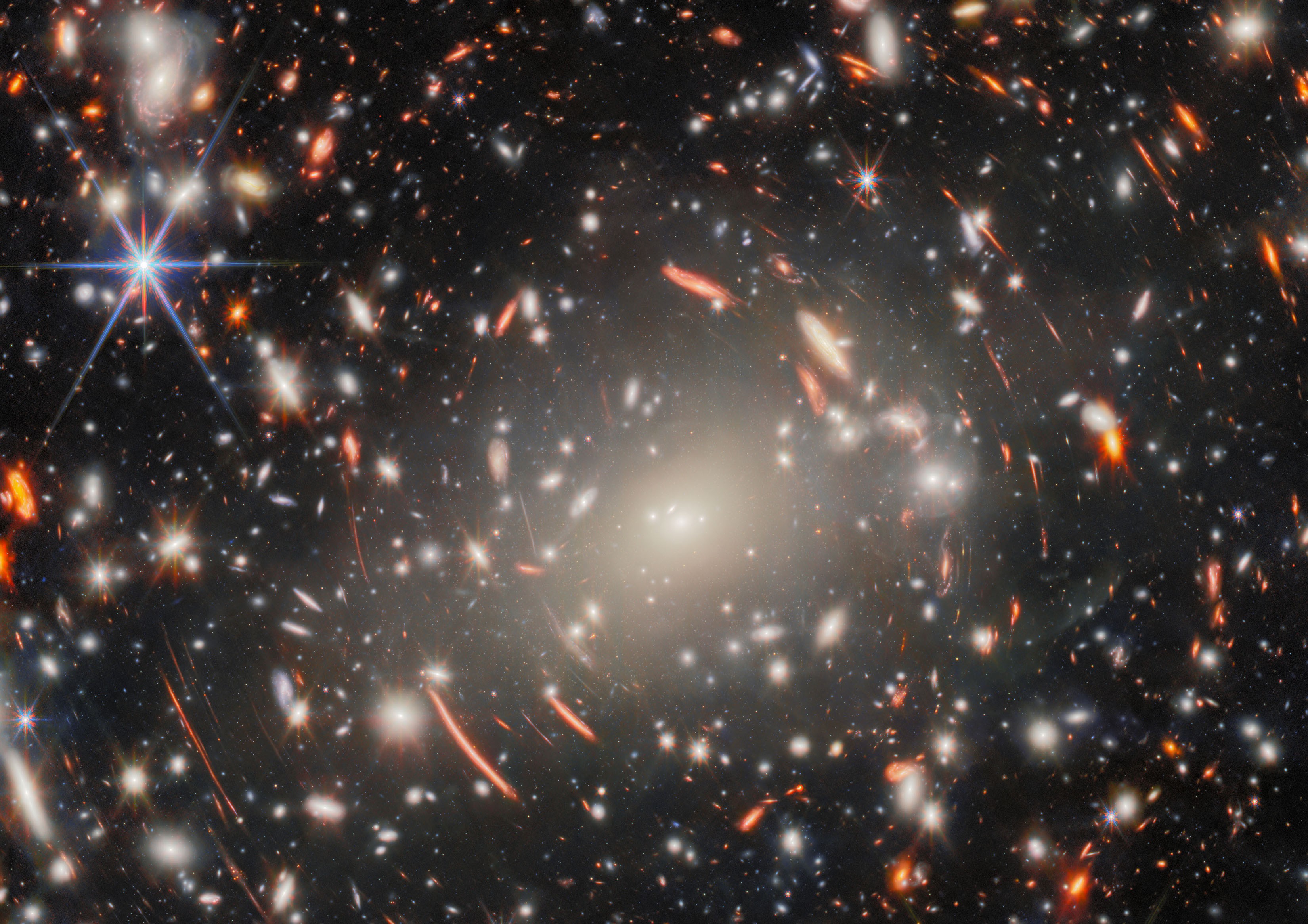 Many galaxies in a cluster, with most appearing stretched or warped in varying ways
