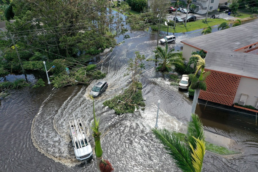 An aerial view of cars and trucks driving through a flooded street.
