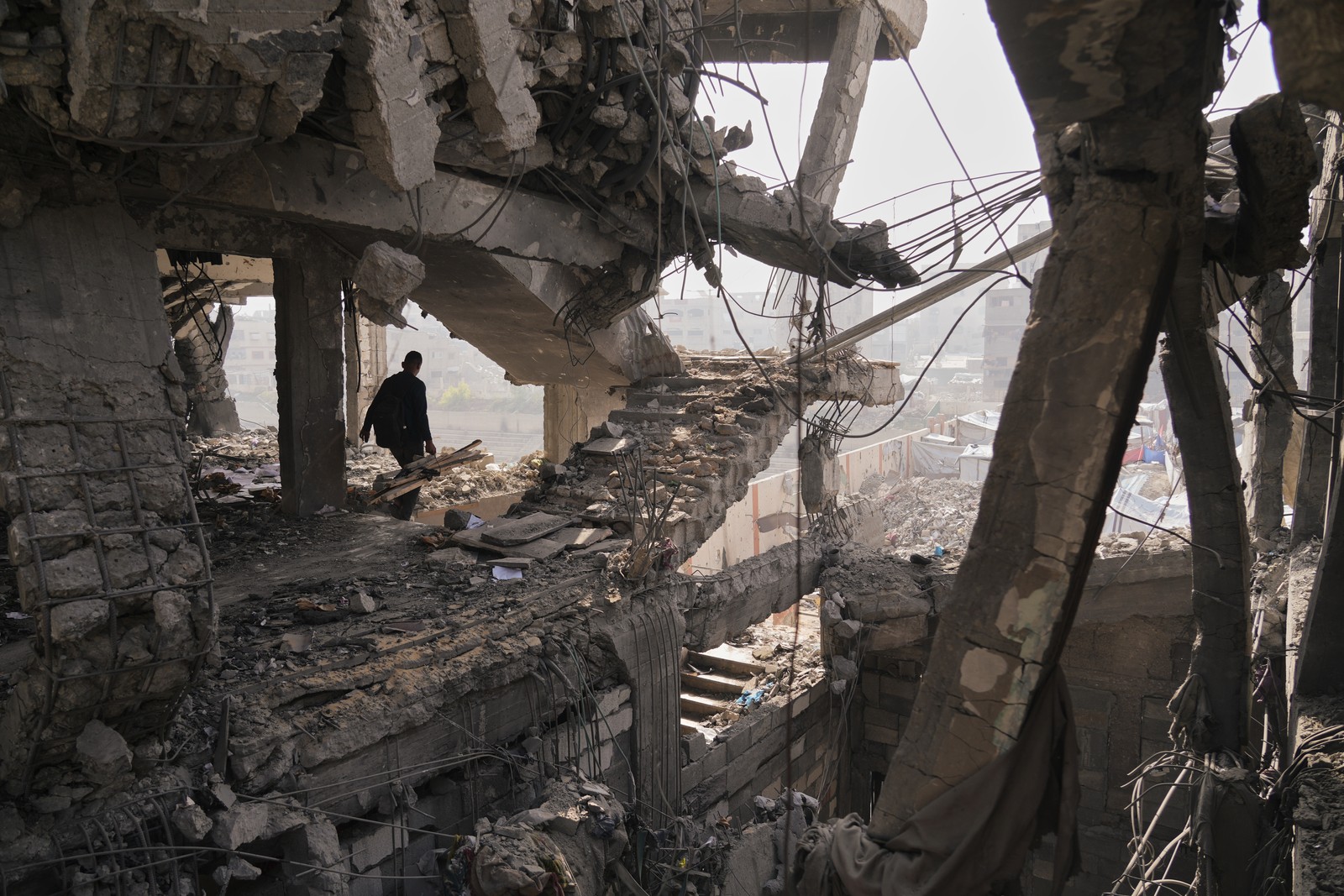 A person walks inside the crumbling ruin of a tall concrete building after it was hit by an airstrike.