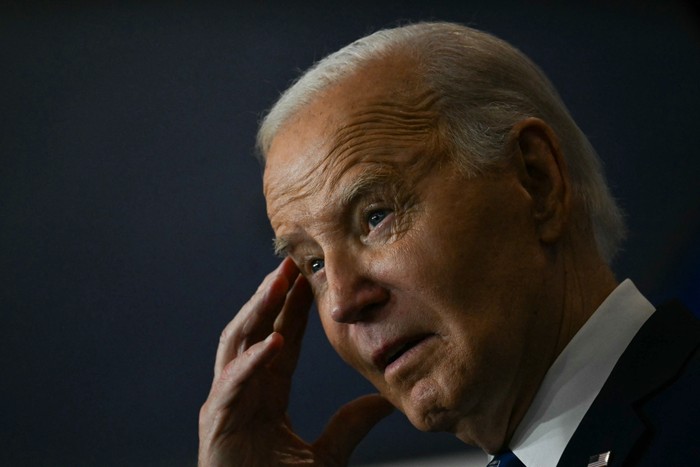 A photo of Joe Biden touching his temple with one hand during his remarks