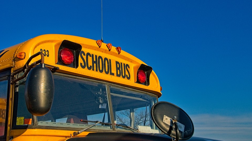 The top of a yellow school bus in front of a blue sky