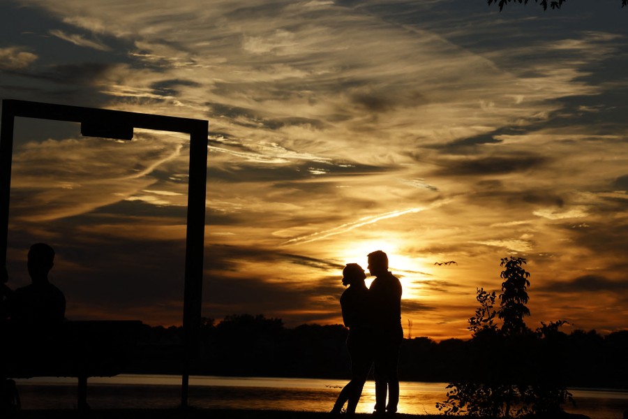 Two people are silhouetted by a sunset.