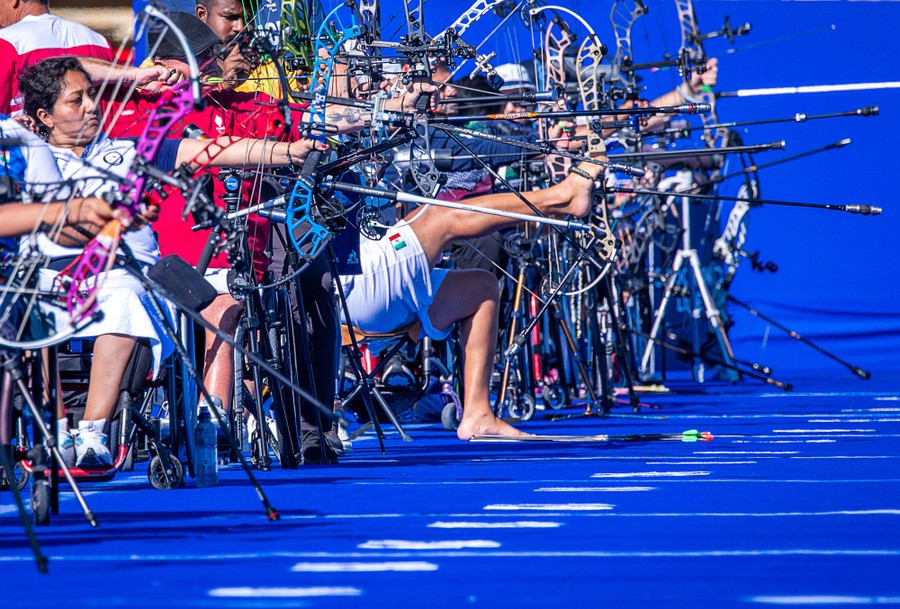 Archers with a variety of disabilities practice side-by-side at a range, displaying many bits of complex gear.