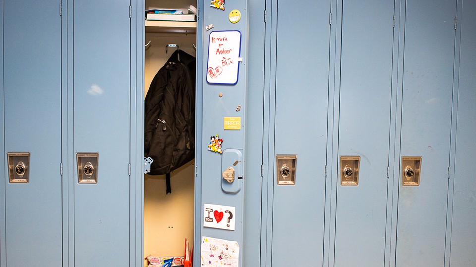 A row of lockers, with one open to show a backpack, textbooks, and interior decorations