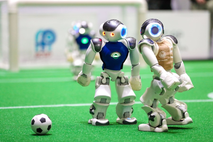 Small humanoid robots face each other during a soccer game.