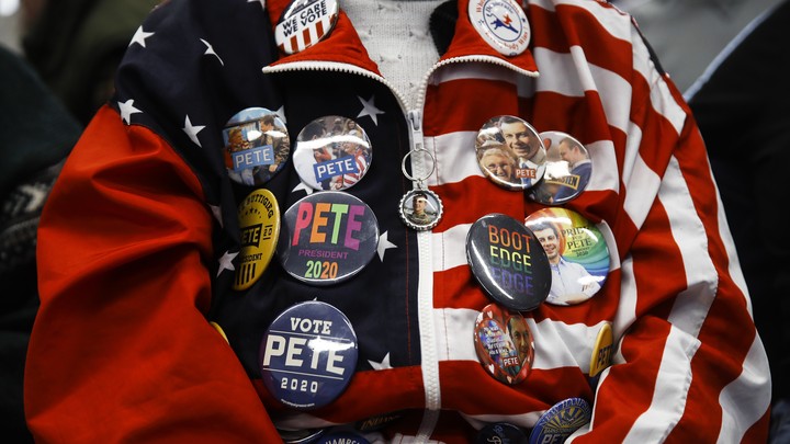 A Pete Buttigieg supporter, seen from the neck down, wears an American-flag jacket covered in pro-Buttigieg buttons.