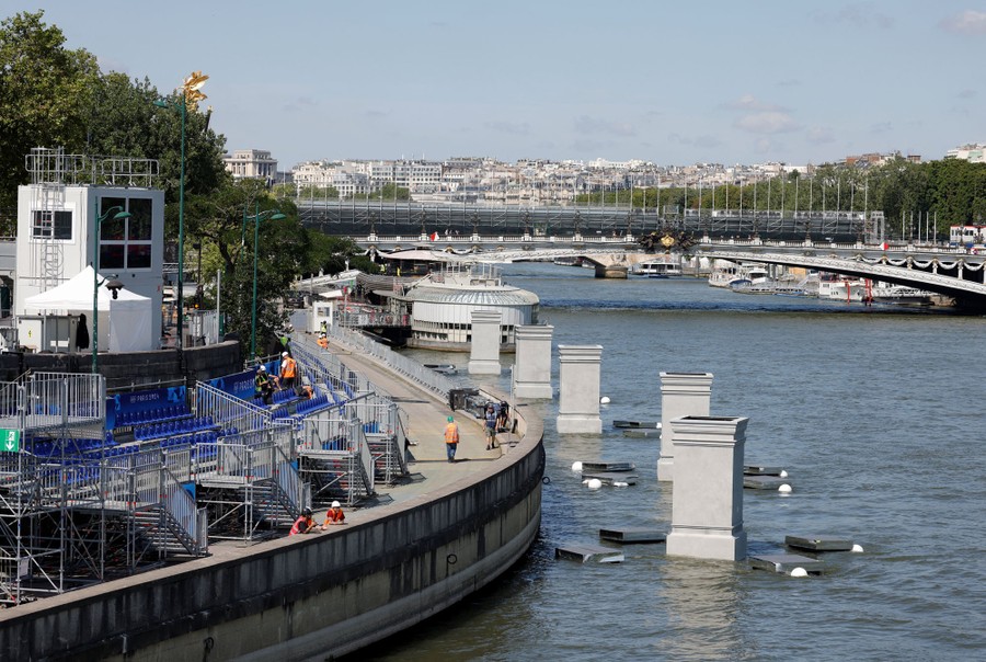 Workers assemble bleachers along a river in Paris.