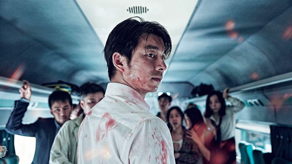 A still from the movie "Train to Busan" showing a bloodied man on a train with other passengers