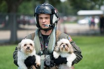 A Naval Aircrewman carrying two dogs.